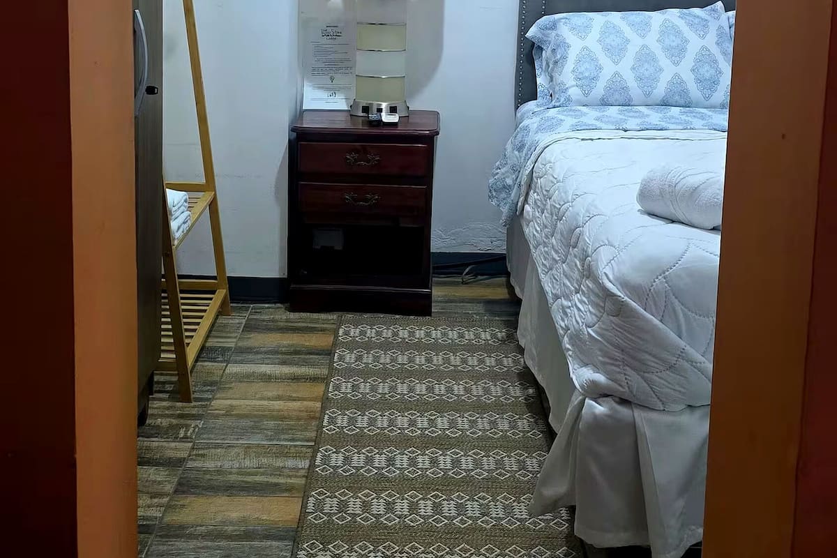 Een slaapkamer met een bed, nachtkastje, lamp en een houten ladder.
