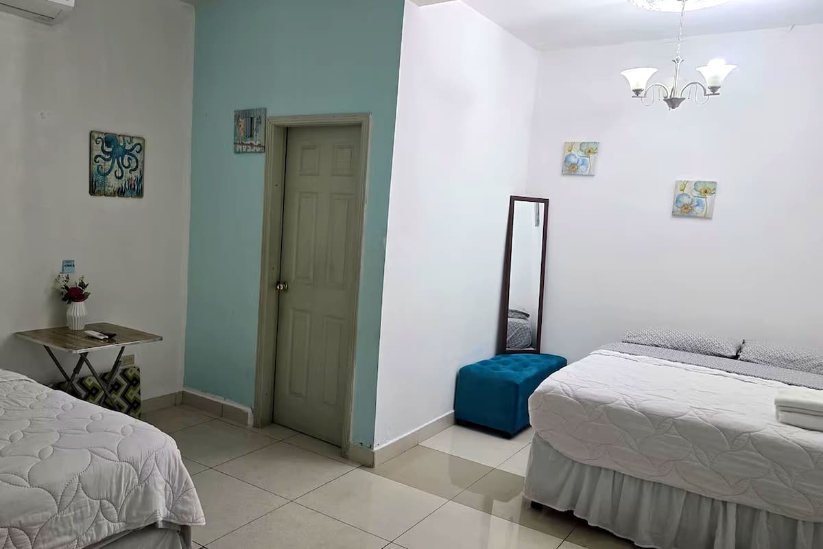 Een slaapkamer met twee bedden, een klein tafeltje met een vaas, een spiegel en een deur.