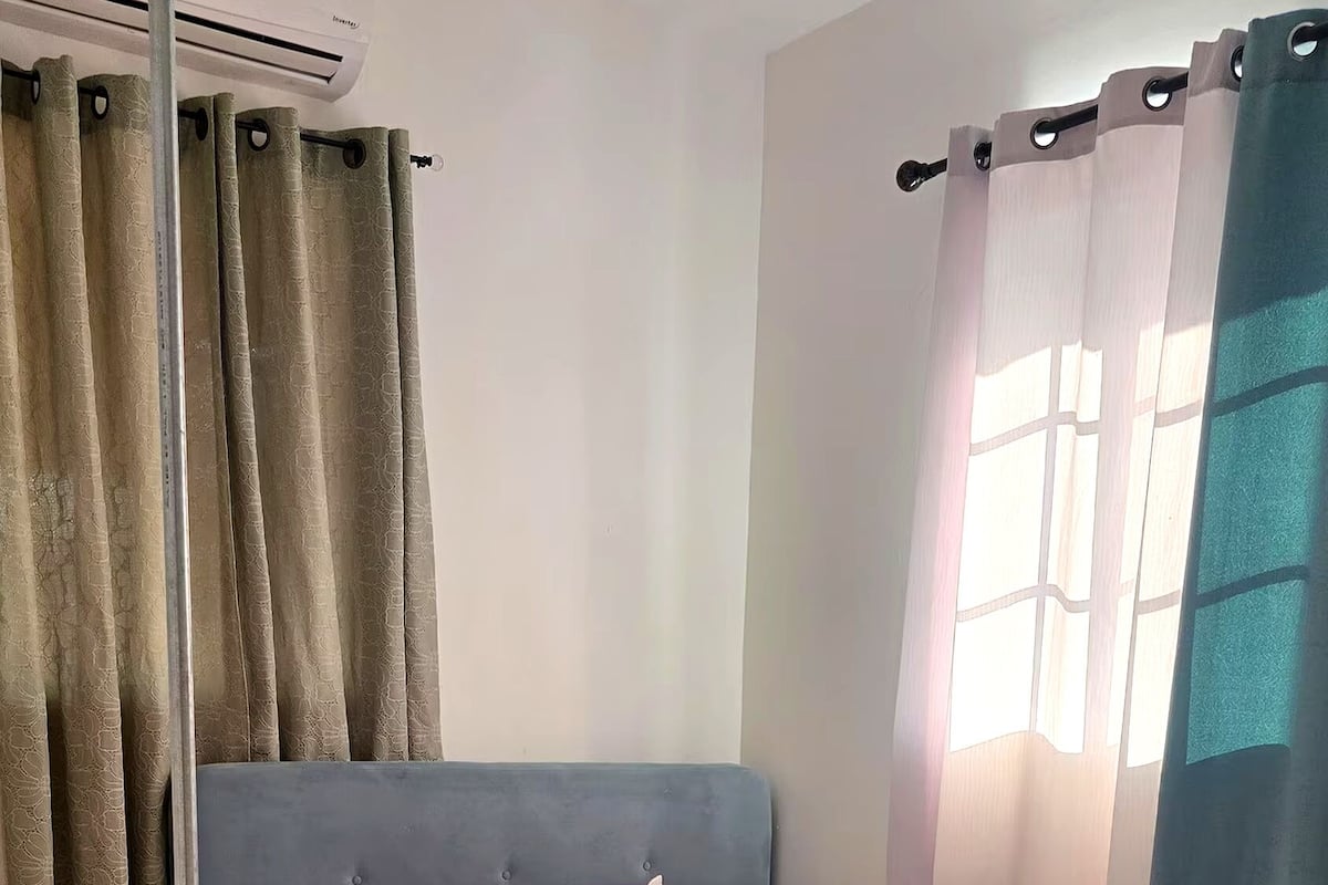 Een slaapkamer met een bed, gordijnen en een raam.