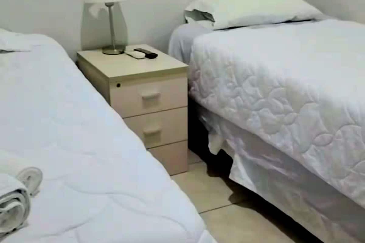 Een hotelkamer met twee bedden, een nachtkastje, een lamp en een ladekast.