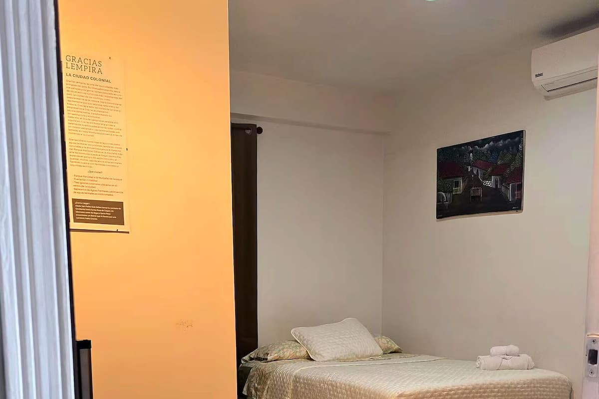 Een hotelkamer met een bed, een bank, een schilderij aan de muur en een deur met een bordje.