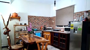 A kitchen with a wooden table, chairs, a stove, and a refrigerator.