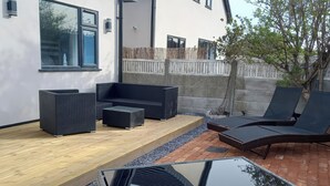 A patio with outdoor furniture, a wooden deck, and a reflective pool. - Mikes Place On The Cove (Rhyl)