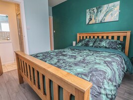 A bedroom with a wooden bed frame, a green wall, and a marble-patterned bedspread.