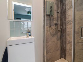 Un baño con ducha, lavabo y espejo.
