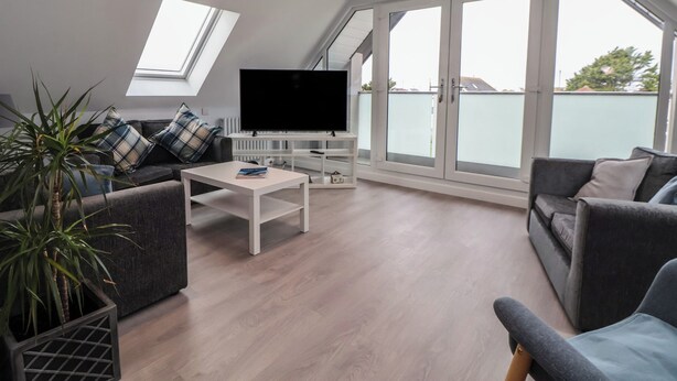 A modern living room with a flat-screen TV, a coffee table, and two sofas. - Mikes Place On The Cove (Rhyl)