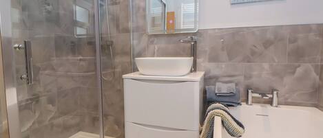 A modern bathroom with a glass shower enclosure, a white sink with a vessel basin, and a bathtub.