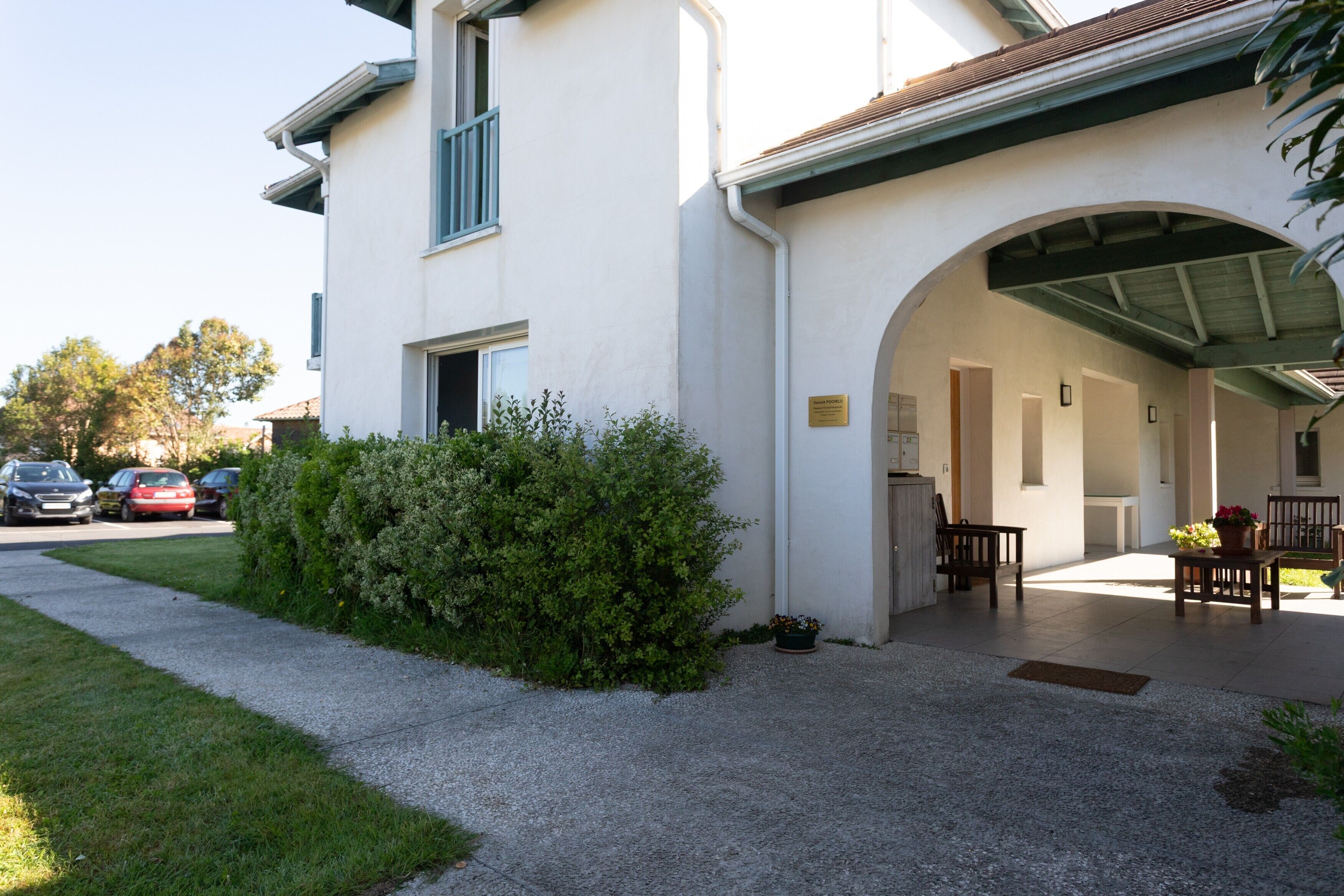 Un bâtiment doté d’un patio couvert, d’un petit jardin et d’un chemin menant à l’entrée.