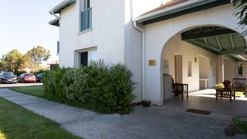 Un bâtiment doté d’un patio couvert, d’un petit jardin et d’un chemin menant à l’entrée.