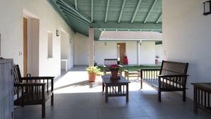A covered patio area with wooden furniture, potted plants, and a view of a building in the background. - T2 Vert Anis Apartment with Wi-Fi (Salies-de-Béarn)