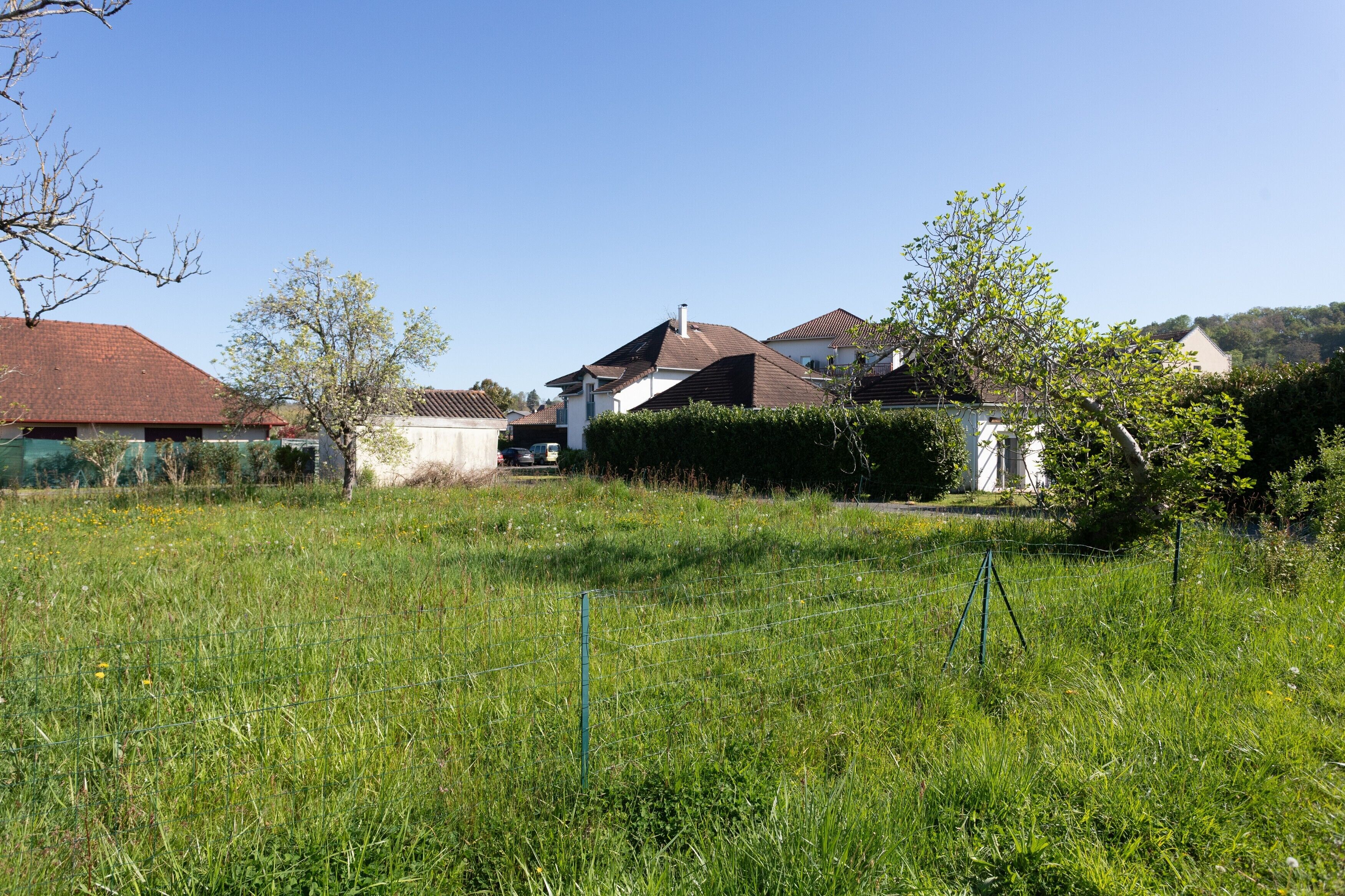 Un quartier résidentiel avec des maisons, un champ verdoyant et un ciel dégagé.