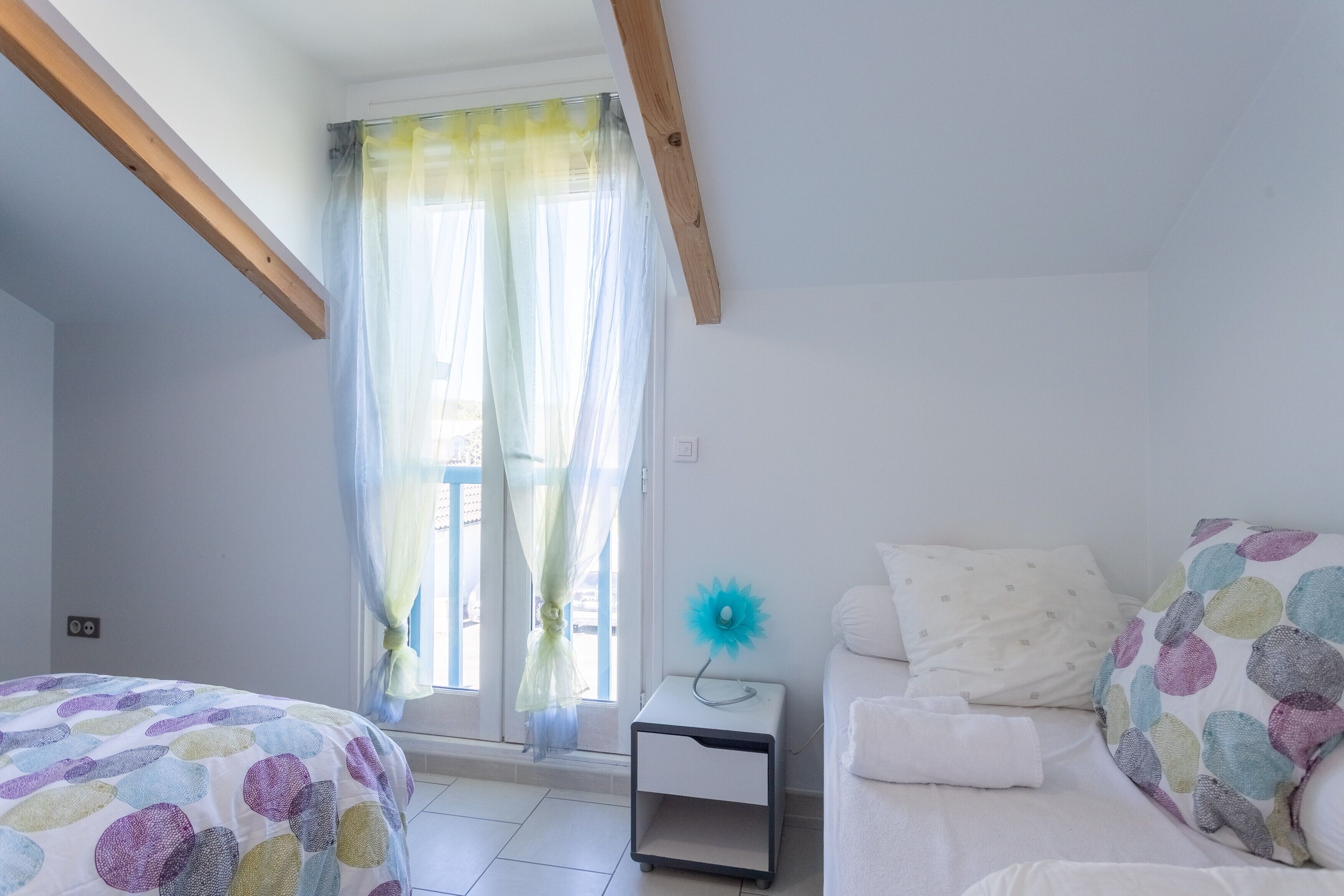 A bedroom with a bed, bedside table, and a window with curtains.