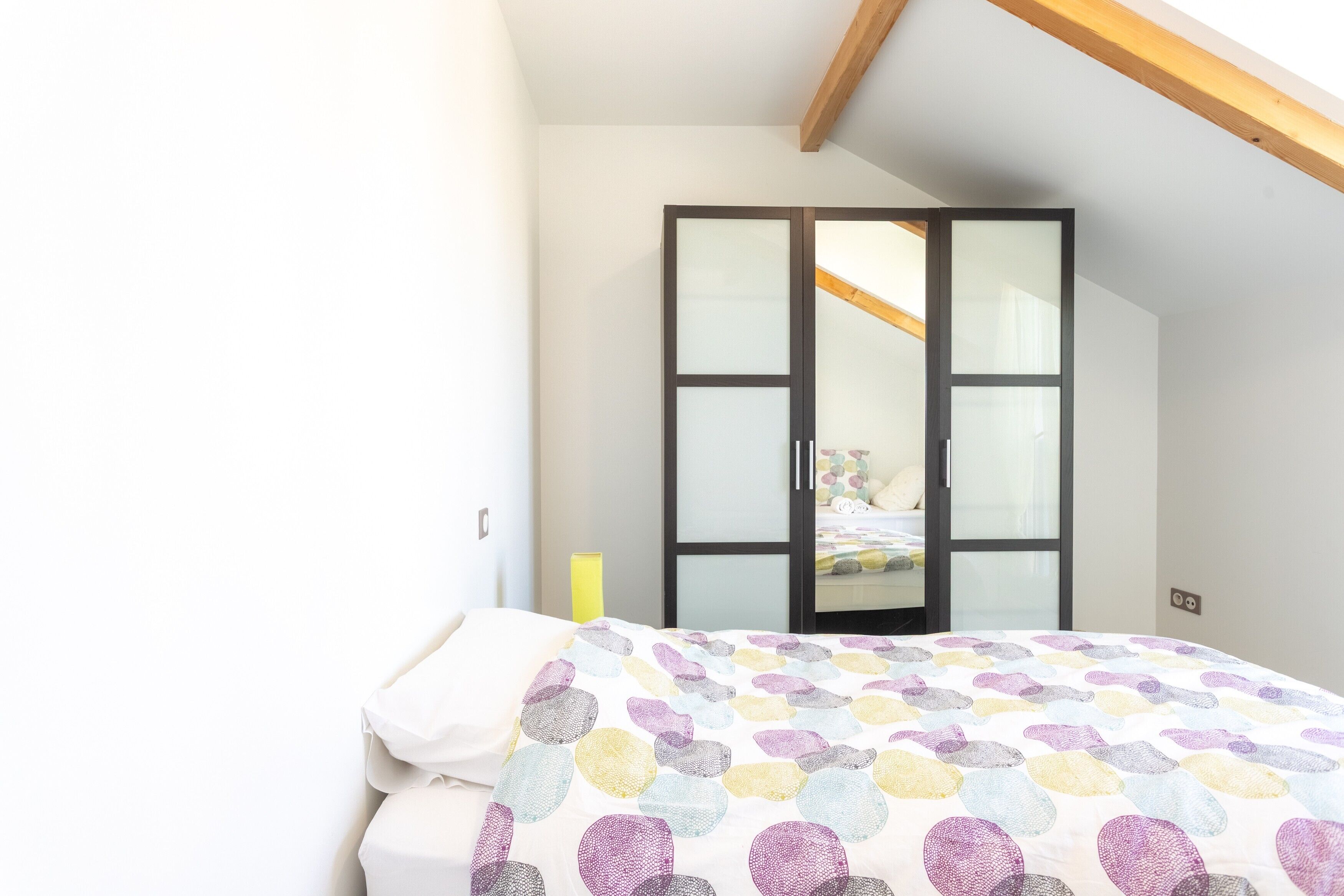 Een slaapkamer met een bed, een kledingkast en een raam.