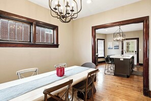 A dining area with a long table, chairs, a chandelier, and a view to a kitchen area. - Spacious Louisville retreat w/ pingpong & backyard (Louisville)