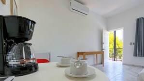 A modern room with a coffee maker, two cups, a table, and a door leading to a balcony. - Shared Pool Oasis  Near Malecon  BBQ  Wi-Fi (La Paz)