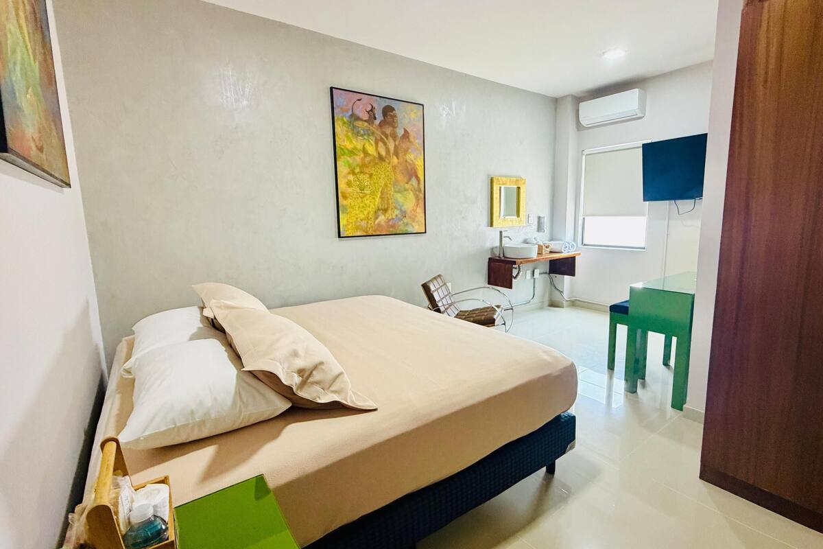 A bedroom with a bed, a chair, a desk, and a wardrobe.