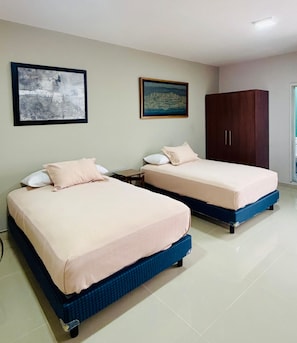 Two beds with blue frames, a wooden wardrobe, and two framed artworks on the wall. - Kundera Hotel Boutique (Colima)