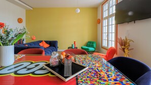 A modern living room with a large TV, colorful seating, and a table with a tray.