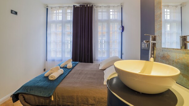 A hotel room with a bed, a large sink, and a window with curtains.