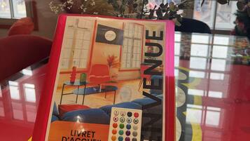 A book titled 'LIVRET D'ACCUEL' with a color wheel and a room layout illustration.