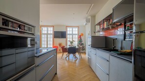 A modern kitchen with grey cabinetry, a built-in oven, and a dining area with a table and chairs.