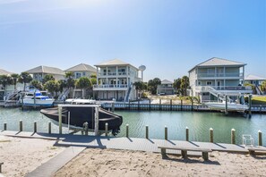 Un port de plaisance où sont amarrés des bateaux, une plage de sable et des villas en bord de mer dotées de balcons.