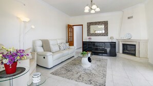 A living room with a sofa, a glass coffee table, a fireplace, and a mirror on the wall. - Holiday Apartment 'Panoramic View Apartment' with Sea View, Wi-Fi and Air Conditioning (Quarteira)