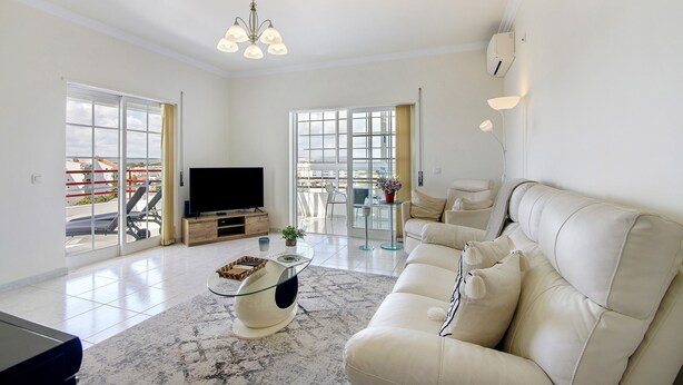 A spacious living room with a large flat-screen TV, a beige sofa, and a glass coffee table. - Holiday Apartment 'Panoramic View Apartment' with Sea View, Wi-Fi and Air Conditioning (Quarteira)