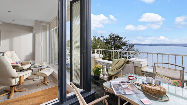 A balcony with a view of the sea, a table with reading materials, and a chair. - Beach View Suite - Sea view, Balcony, Wi-fi (Torquay)