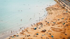 A beach with people swimming and sunbathing, a sandy shore, and a clear blue sea. - Beach View Suite - Sea view, Balcony, Wi-fi (Torquay)