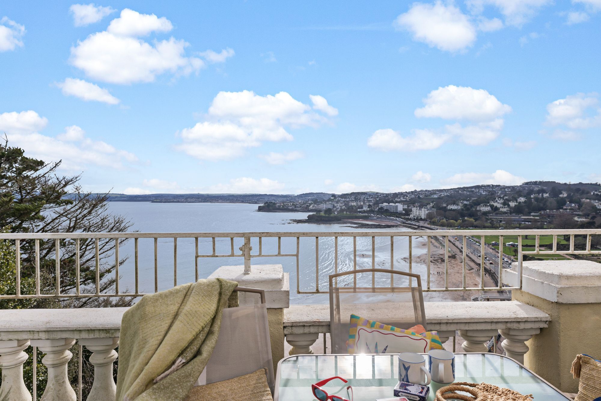 Un balcon donnant sur une étendue d’eau et sur une vue panoramique de la ville au loin.