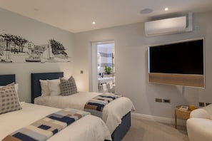 A hotel room with two beds, a TV, an air conditioner, and a view of the city. - 4 The Reach - Pool & Spa facilities, Sea views, Pet friendly (Salcombe)