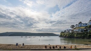 A beach with people meditating, a calm sea, and buildings on a hillside. - 4 The Reach - Pool & Spa facilities,  Sea views, Pet friendly (Salcombe)