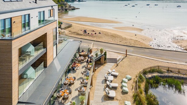 A modern building with a rooftop terrace, outdoor seating area, and a view of the beach and sea. - 4 The Reach - Pool & Spa facilities,  Sea views, Pet friendly (Salcombe)