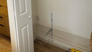 Ein Schrank mit einer weißen Tür, einem Metallregal und einem Drahtgitterregal.