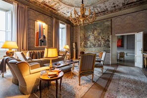 A spacious living room with a grand chandelier, a large painting, and a view of the dining area. - Palazzo Angelico: Luxury Apartment on the Lungarno (Firenze)