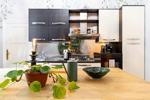 A kitchen with a wooden table, a potted plant, a green vase, and a green bowl. - Palazzo Angelico: Luxury Apartment on the Lungarno (Firenze)