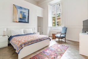 Ein Schlafzimmer mit einem großen Bett, einem Sessel, einem Fernseher und einem Fenster mit Aussicht.