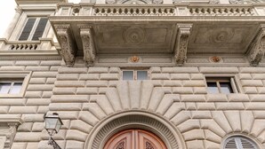 Una puerta de madera grande y elaborada con tallas detalladas, ubicada en la fachada de un edificio de estilo arquitectónico clásico.