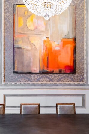 A dining area with a large abstract painting on the wall, a chandelier, and a table with chairs. - Palazzo Angelico: Luxury Apartment on the Lungarno (Firenze)