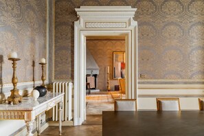 A room with a marble fireplace, a dining table, and a patterned wallpaper. - Palazzo Angelico: Luxury Apartment on the Lungarno (Firenze)