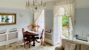 Comedor con candelabro, una mesa con sillas, un espejo y vistas a través de una ventana.