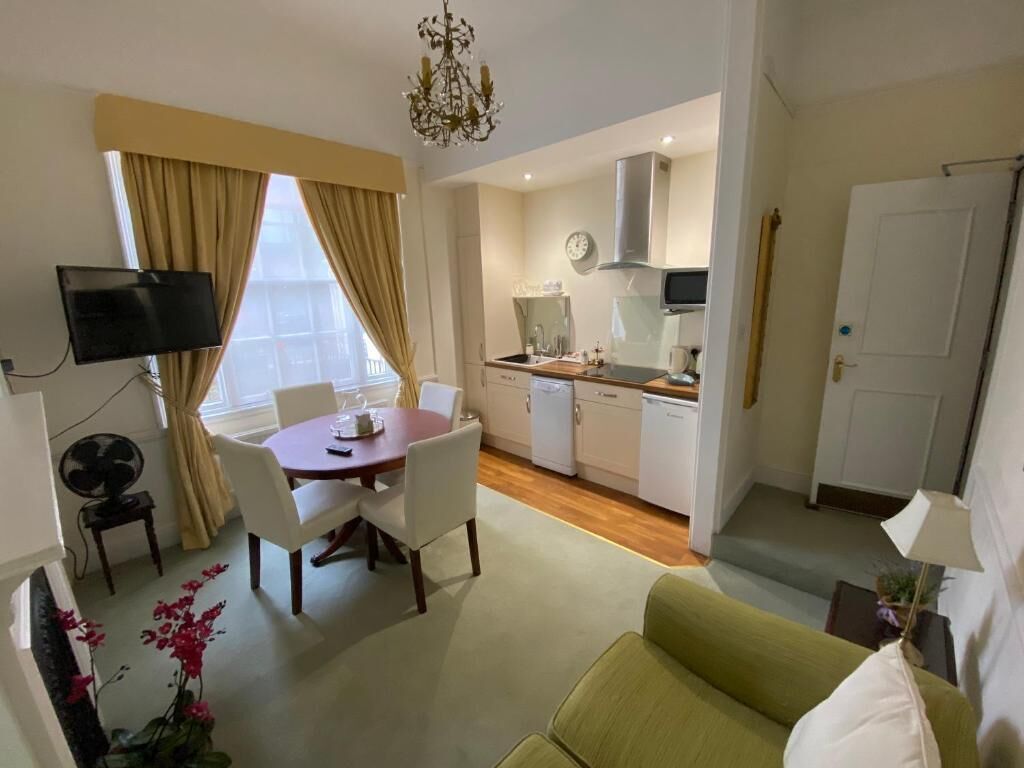 A compact living space with a dining area, kitchenette, and a green sofa.