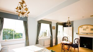 Un dormitorio con cama, una mesa con sillas, chimenea y candelabro.