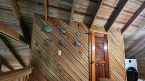 A wooden interior with a sloped ceiling, a wooden door, and a washing machine. - Sandy Bay Island Retreat w/Private Dock, Reef Snorkeling, Pool & Walk to Beach (Roatán)