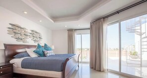 A bedroom with a large bed, a nightstand, a wall art piece, and a balcony with curtains. - Private Terrace  BBQ  Pool Walk to Beach (La Paz)