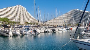 A marina with multiple boats docked, a large building with balconies, and a clear blue sky. - Apartment 'Grand Luxe Vue Mer Exclusif' with Sea View, Wi-Fi and Air Conditioning (Villeneuve-Loubet)