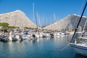 A marina with multiple boats docked, a large building with balconies, and a clear blue sky. - Apartment 'Grand Luxe Vue Mer Exclusif' with Sea View, Wi-Fi and Air Conditioning (Villeneuve-Loubet)