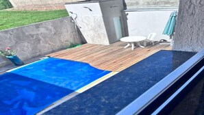 Une piscine sur le toit, avec une terrasse en bois et une petite table.