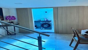 Une chambre d’hôtel moderne avec un escalier, un coin repas et un lave-linge visible à travers une porte.